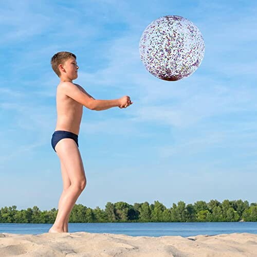 Jongen speelt met strandbal op het strand.